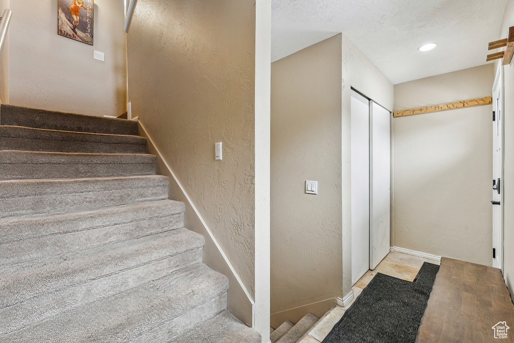 Stairs with recessed lighting, baseboards, a textured ceiling, and a textured wall