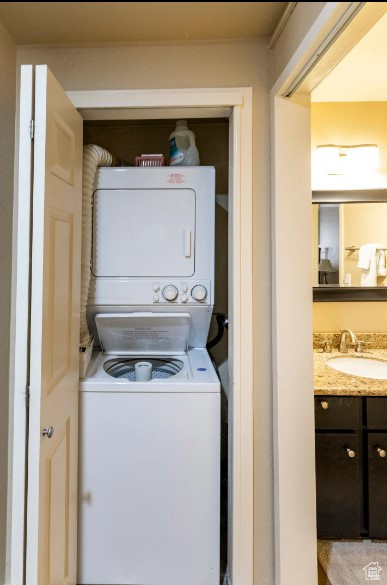 Washroom featuring sink and stacked washing maching and dryer