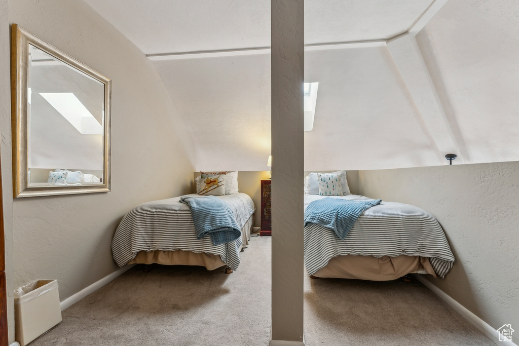 Bedroom featuring baseboards, lofted ceiling, carpet, and a textured wall
