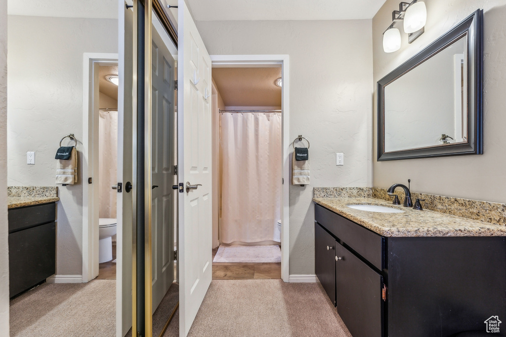 Full bath with a shower with curtain, toilet, vanity, and baseboards