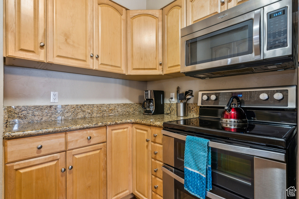 Kitchen featuring light brown cabinetry, appliances with stainless steel finishes, and light stone countertops