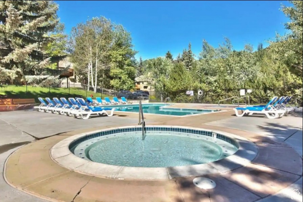 Pool featuring a patio, a hot tub, and fence