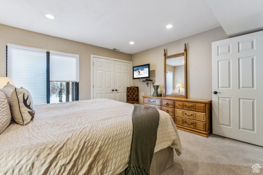 Bedroom with recessed lighting, visible vents, light colored carpet, and a closet