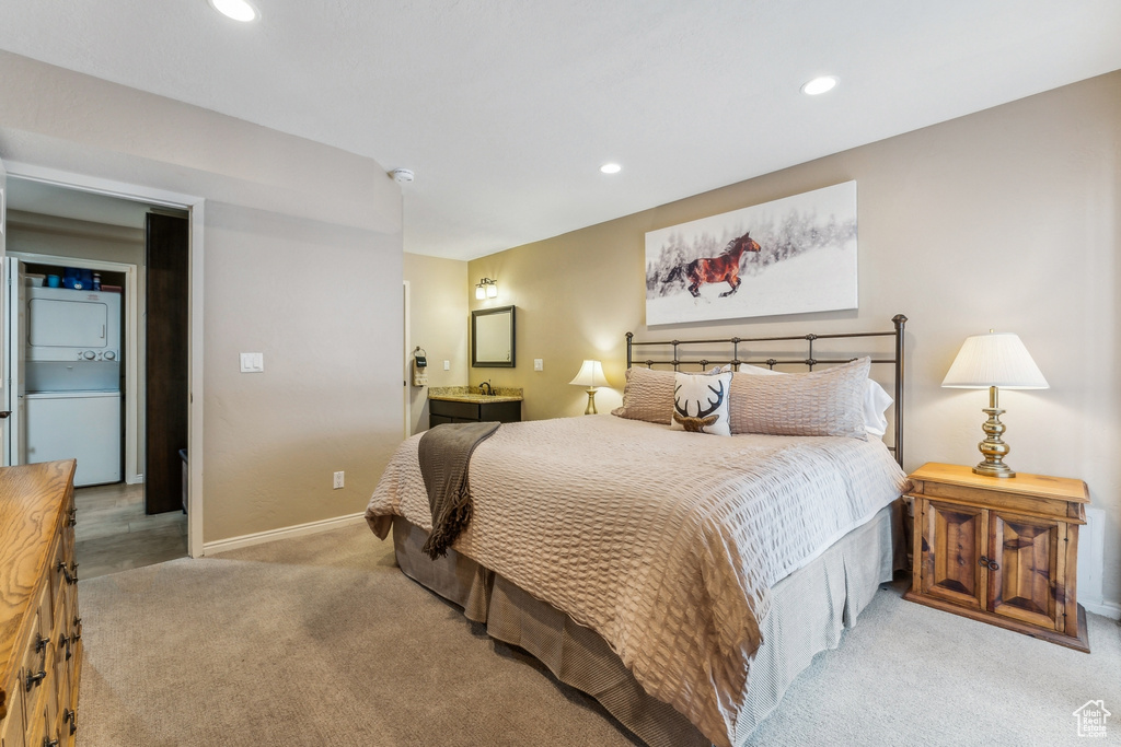 Bedroom with recessed lighting, stacked washer / drying machine, light carpet, and baseboards