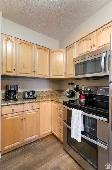 Kitchen with appliances with stainless steel finishes, light brown cabinets, and light wood-type flooring