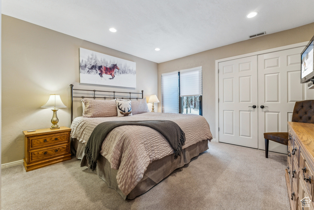 Bedroom with a closet, visible vents, light colored carpet, and recessed lighting