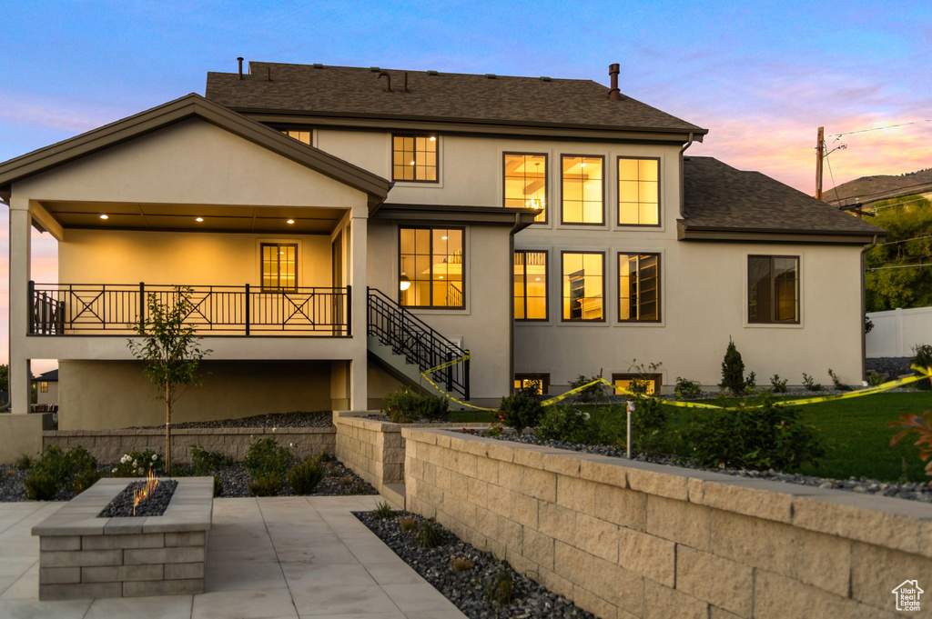 Back house at dusk featuring a patio and a fire pit