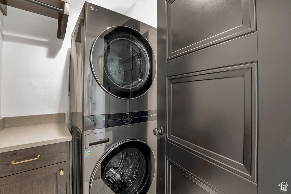 Laundry room with stacked washer / drying machine and cabinets