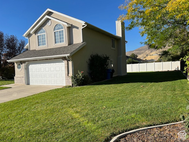 View of side of property featuring a mountain view, a garage, and a lawn