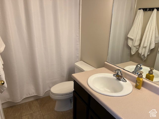 Bathroom featuring toilet, vanity, a shower with shower curtain, and tile patterned flooring