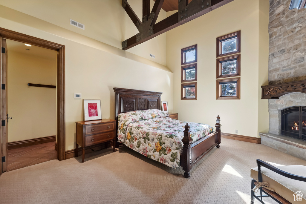 Carpeted bedroom featuring a fireplace, a high ceiling, and ceiling fan