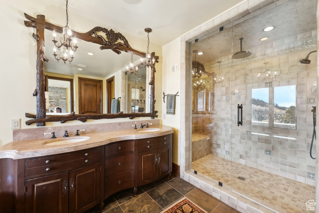 Bathroom with a shower with door, an inviting chandelier, and vanity