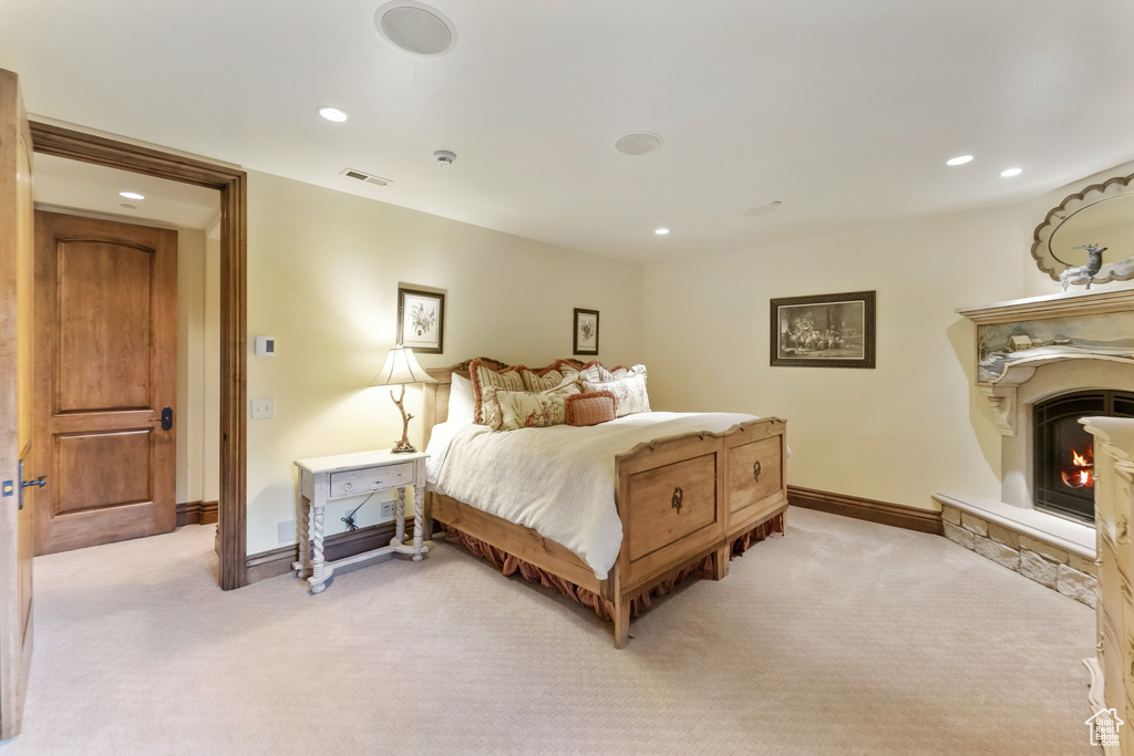 Bedroom with light colored carpet and a fireplace