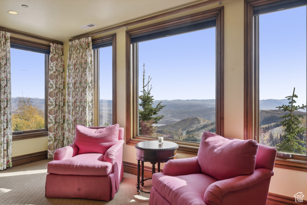 Living area featuring light carpet, a mountain view, and plenty of natural light