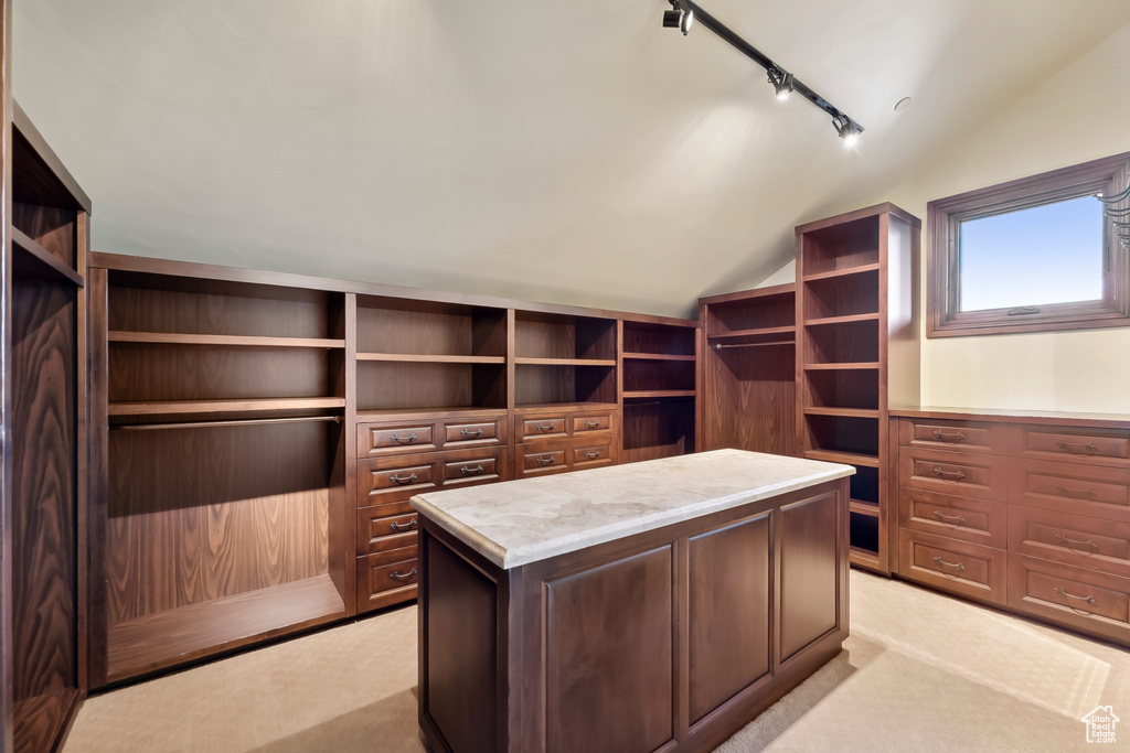 Walk in closet featuring light colored carpet and vaulted ceiling