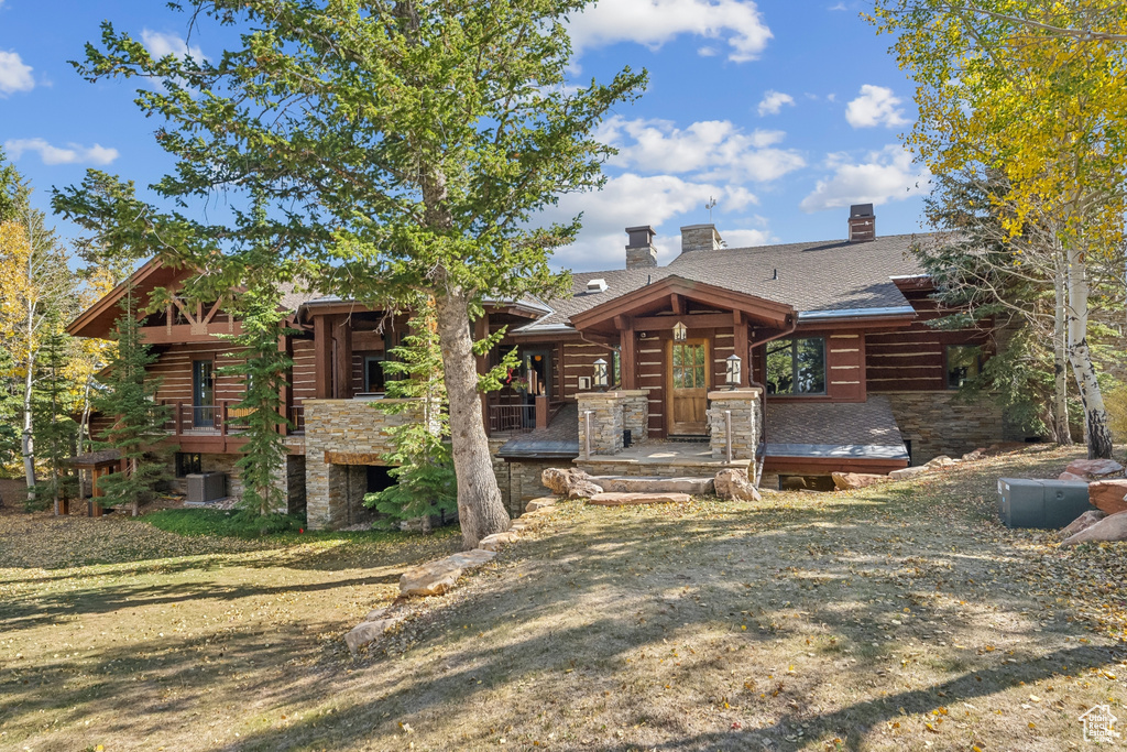 Log-style house with cooling unit, a front yard, and a wooden deck