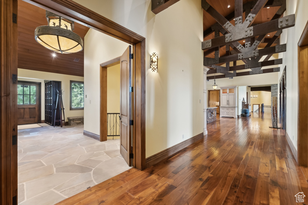 Hallway with high vaulted ceiling, beamed ceiling, and light hardwood / wood-style flooring