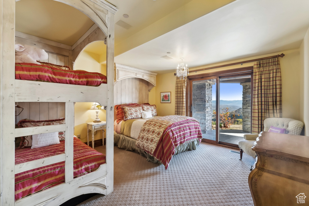 Carpeted bedroom featuring access to outside and an inviting chandelier