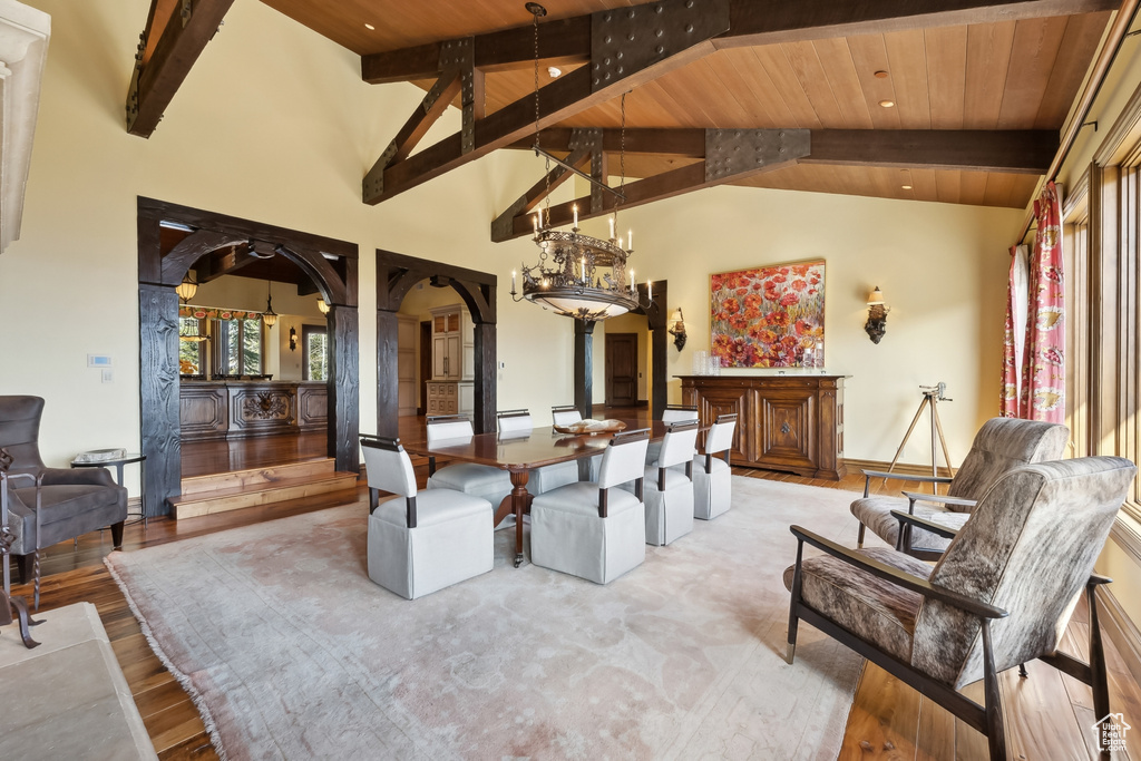 Dining room with light hardwood / wood-style flooring, beam ceiling, high vaulted ceiling, and wooden ceiling