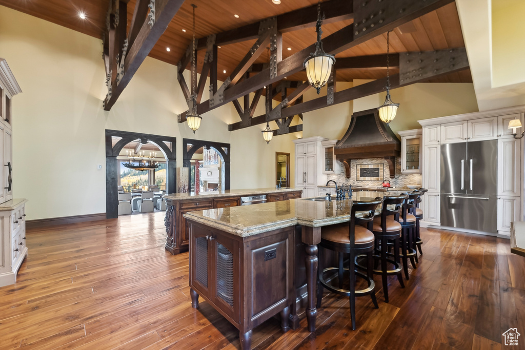 Kitchen with appliances with stainless steel finishes, wood ceiling, white cabinetry, and a large island