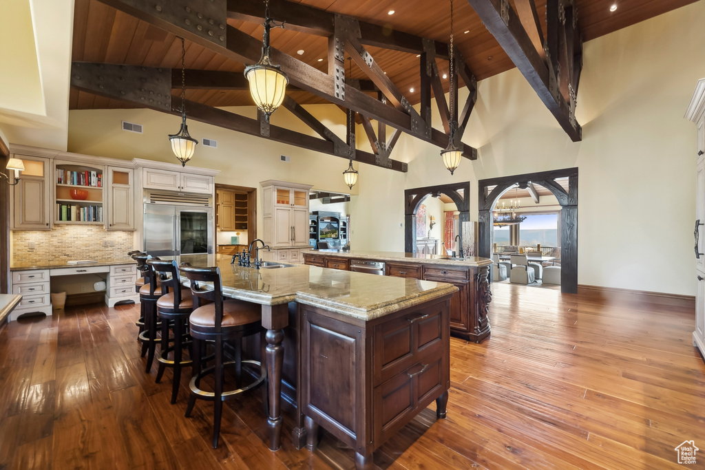 Kitchen with a spacious island, dark hardwood / wood-style flooring, stainless steel appliances, wooden ceiling, and high vaulted ceiling