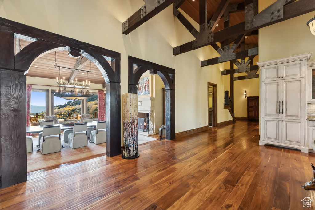 Interior space featuring wood ceiling, beam ceiling, wood-type flooring, an inviting chandelier, and high vaulted ceiling