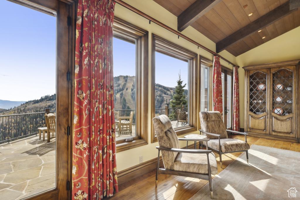 Sunroom featuring lofted ceiling with beams, a mountain view, and wooden ceiling