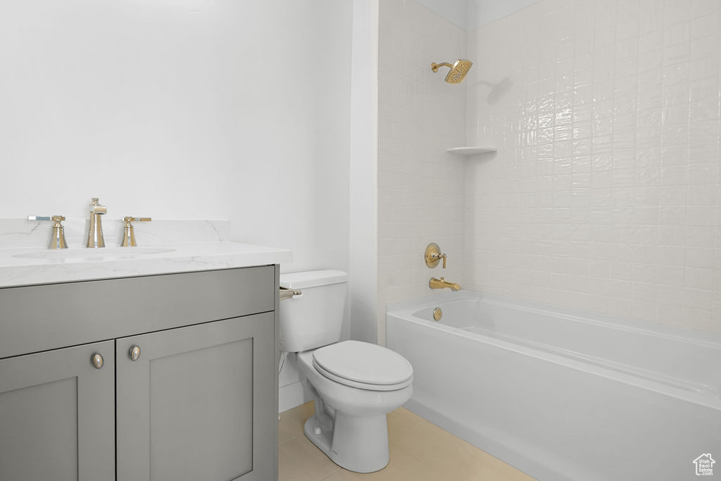 Full bathroom featuring vanity, tiled shower / bath combo, toilet, and tile patterned floors