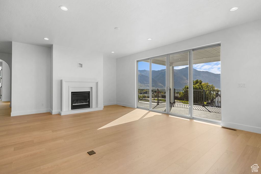 Unfurnished living room with light hardwood / wood-style flooring and a mountain view