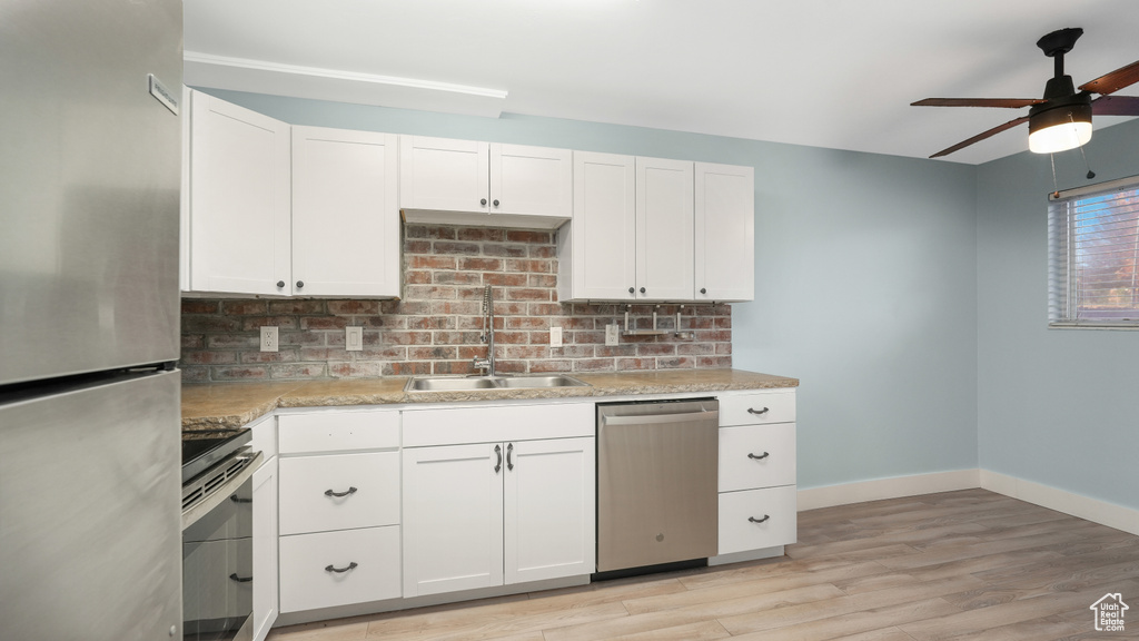 Kitchen featuring sink, appliances with stainless steel finishes, white cabinetry, and light hardwood / wood-style floors