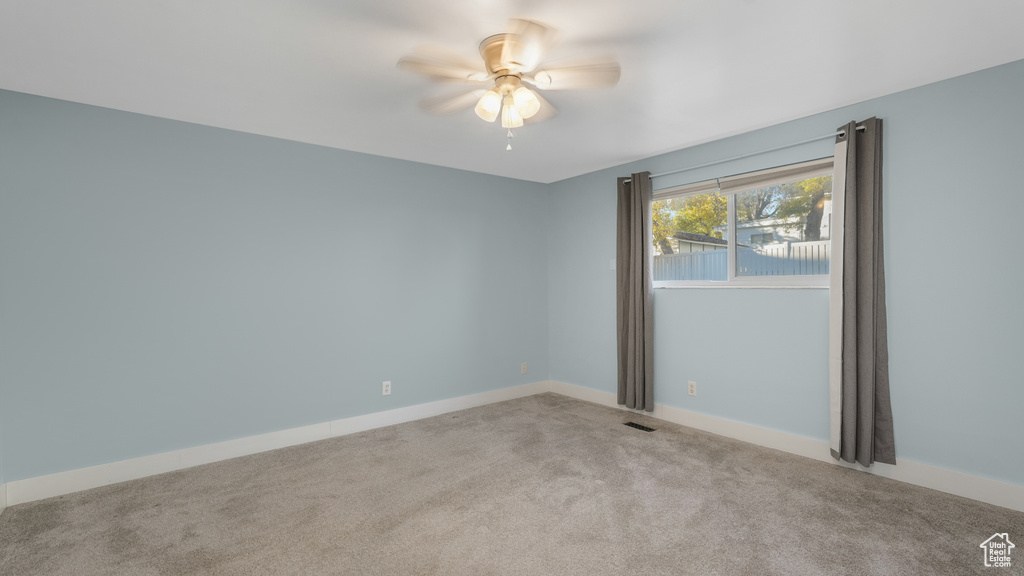 Carpeted empty room featuring ceiling fan