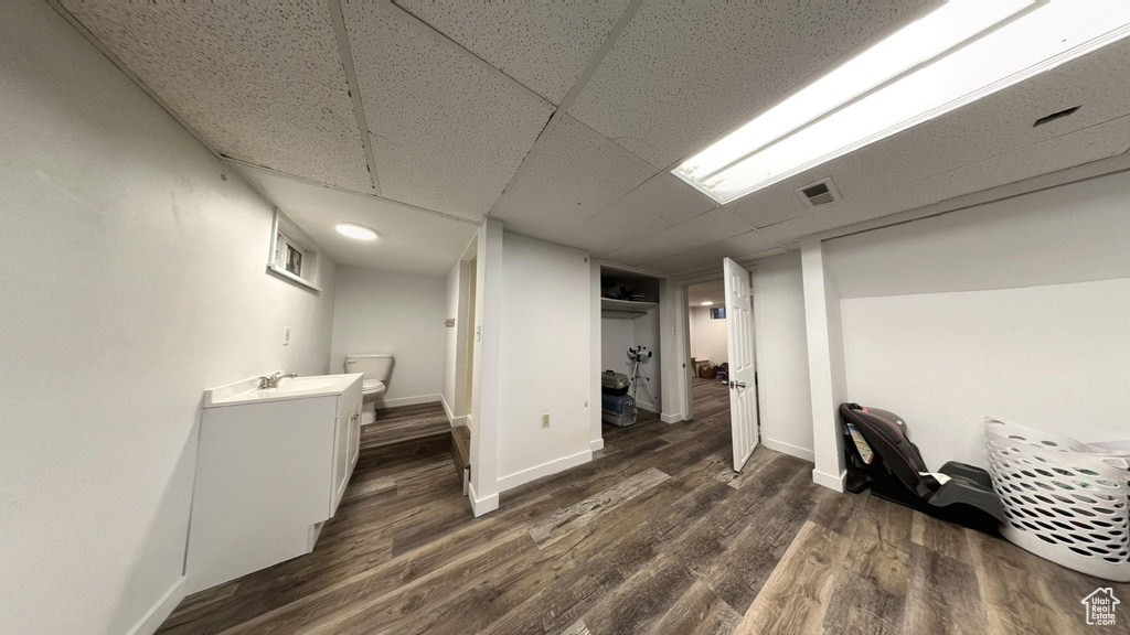 Basement featuring dark wood-type flooring, a paneled ceiling, and sink