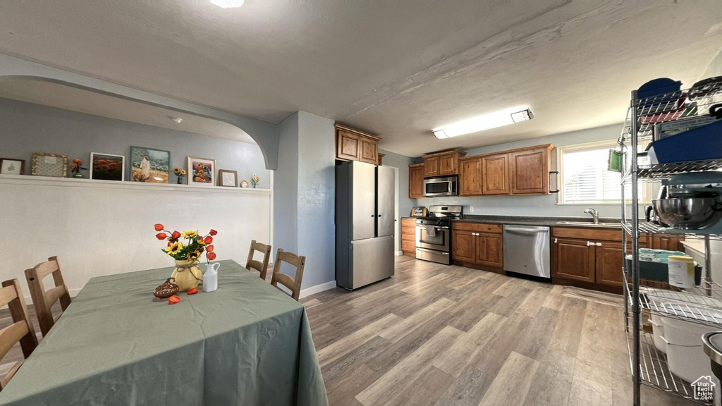 Kitchen with light hardwood / wood-style floors, stainless steel appliances, and sink