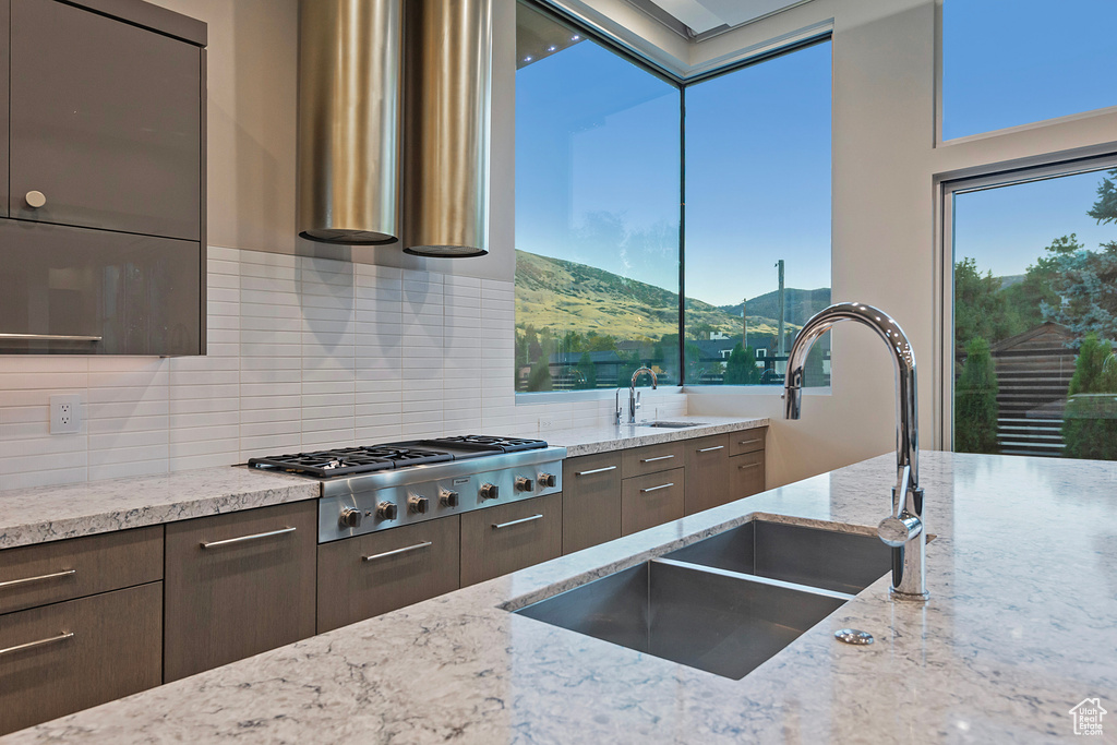 Kitchen with stainless steel gas cooktop, a mountain view, backsplash, sink, and light stone counters