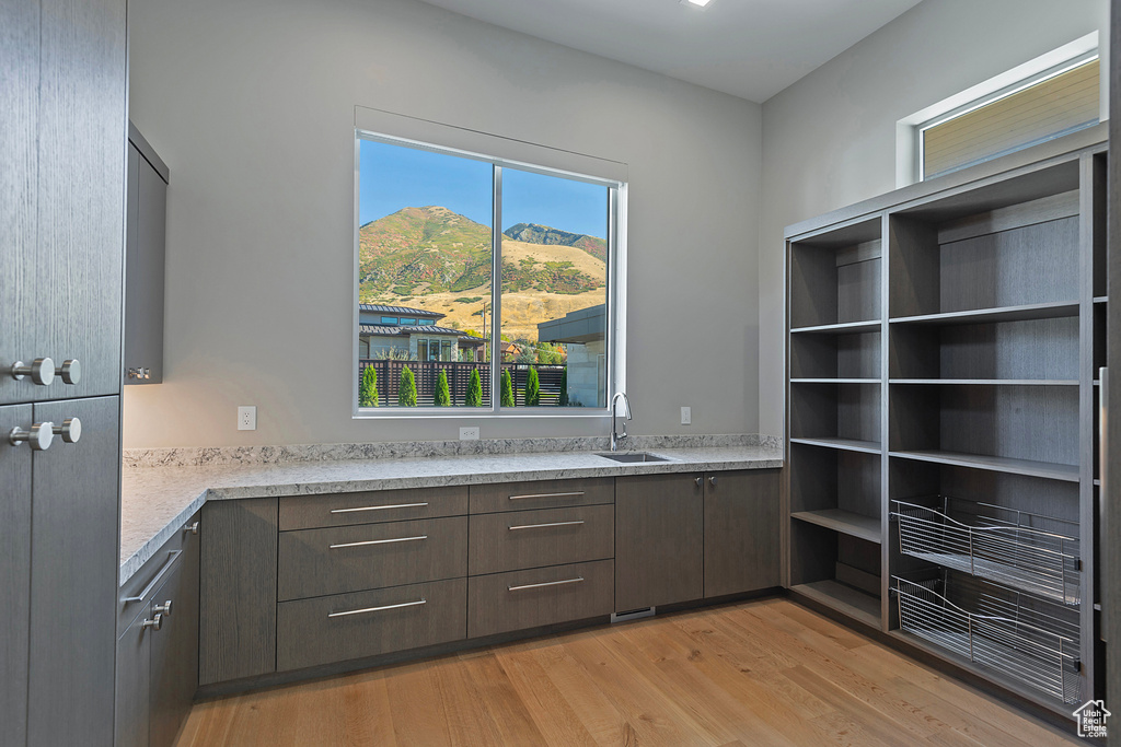 Kitchen featuring light stone countertops, sink, light wood-type flooring, dark brown cabinetry, and a mountain view