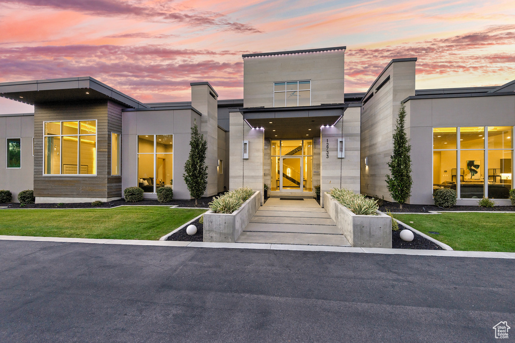 Exterior entry at dusk featuring a lawn