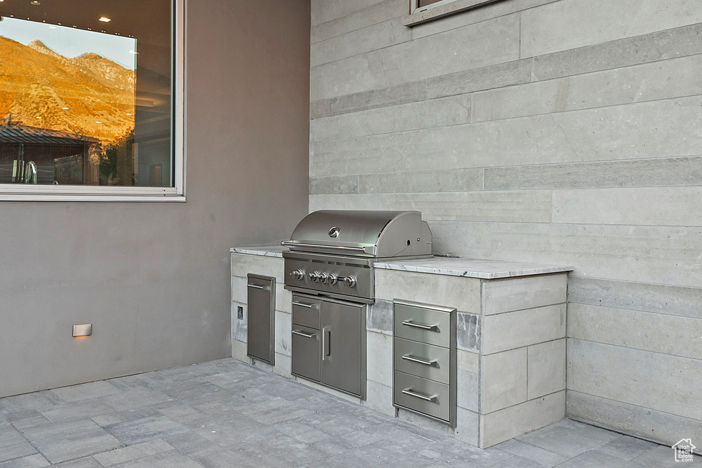 View of patio with exterior kitchen and a grill