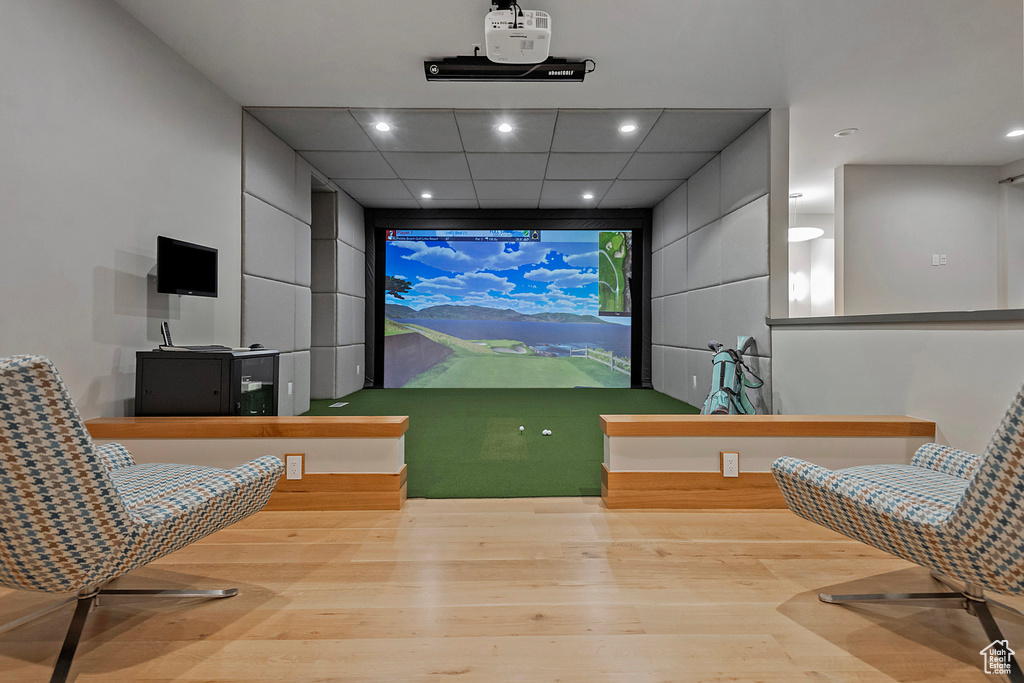 Recreation room with a paneled ceiling, light hardwood / wood-style floors, and golf simulator