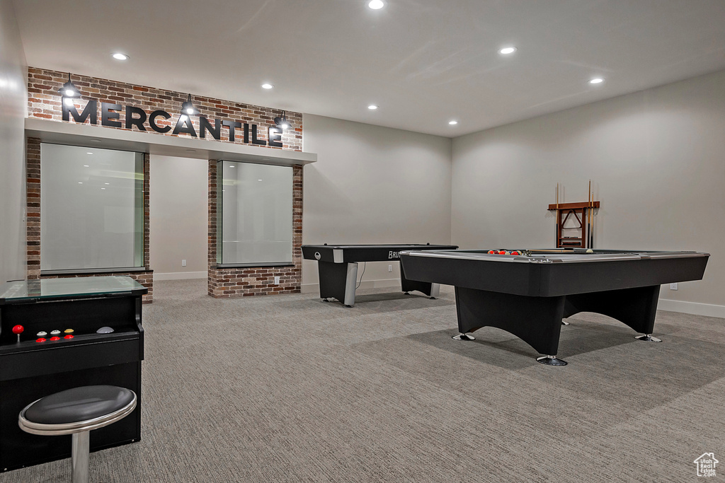 Recreation room featuring brick wall and light carpet