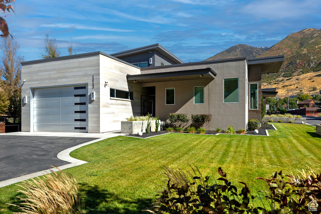 Modern home featuring a mountain view, a front lawn, and a garage