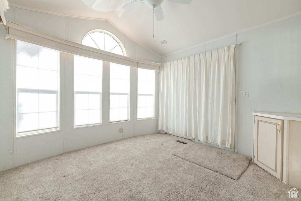 Unfurnished room featuring light carpet, a healthy amount of sunlight, vaulted ceiling, and ceiling fan