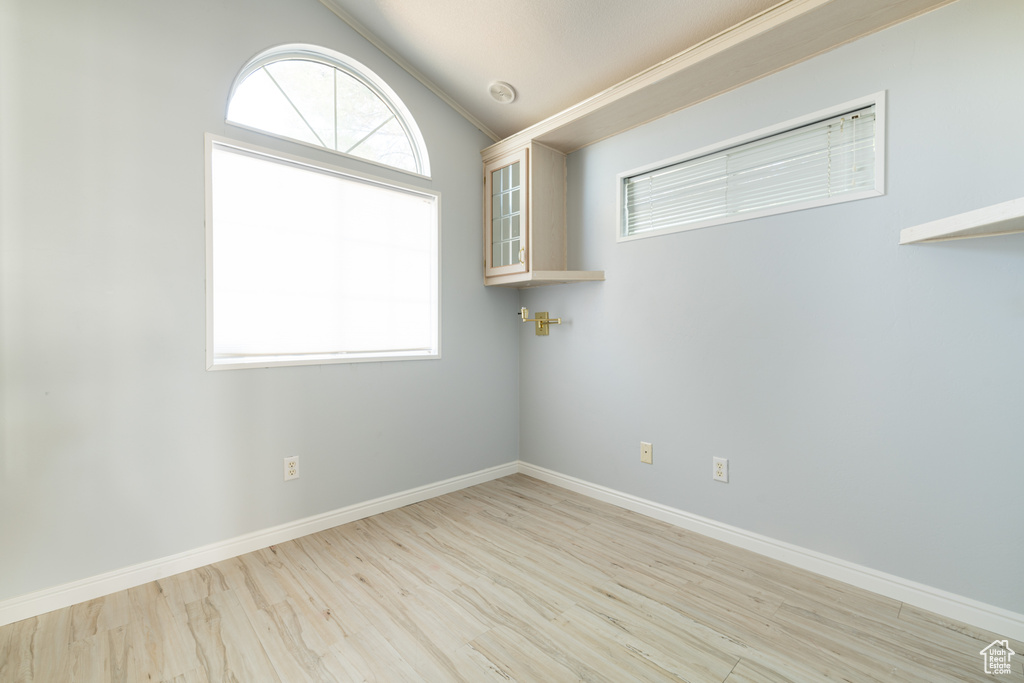 Empty room with lofted ceiling and light wood-type flooring