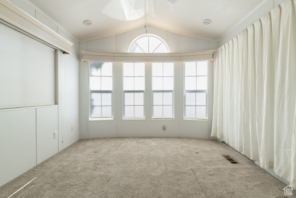 Carpeted empty room featuring vaulted ceiling