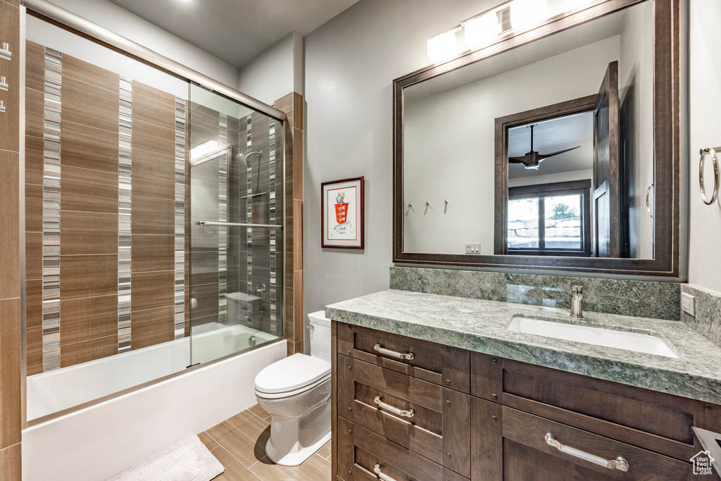 Bathroom featuring toilet, vanity, and shower / bath combination with glass door
