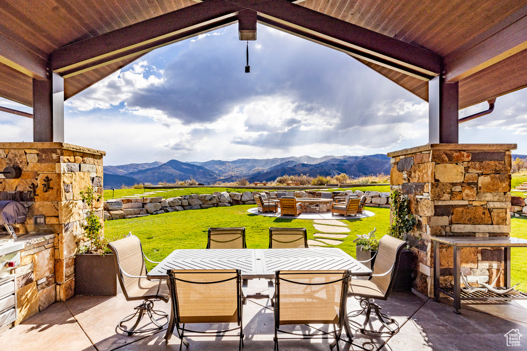 View of patio / terrace featuring outdoor dining area, a mountain view, and an outdoor living space with a fireplace
