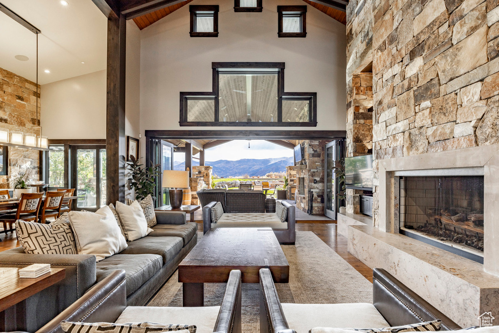 Living room with high vaulted ceiling, wood finished floors, and a fireplace