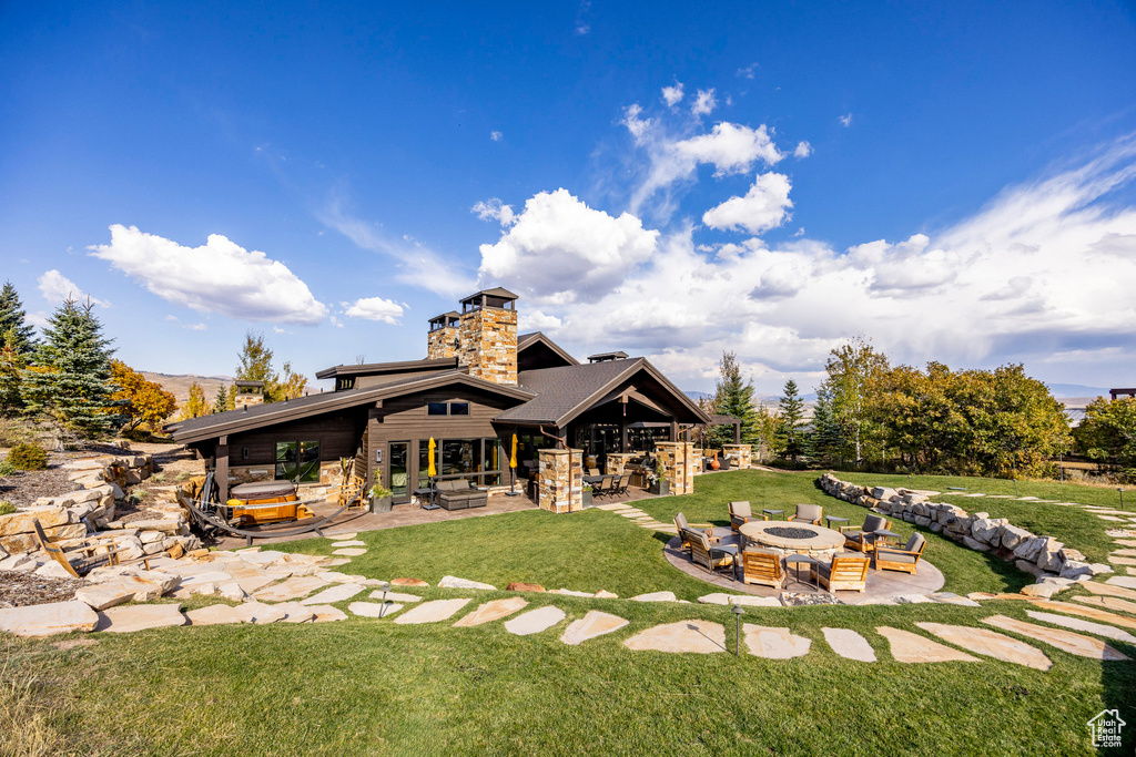 Rear view of property with a fire pit, a patio, a chimney, and a lawn