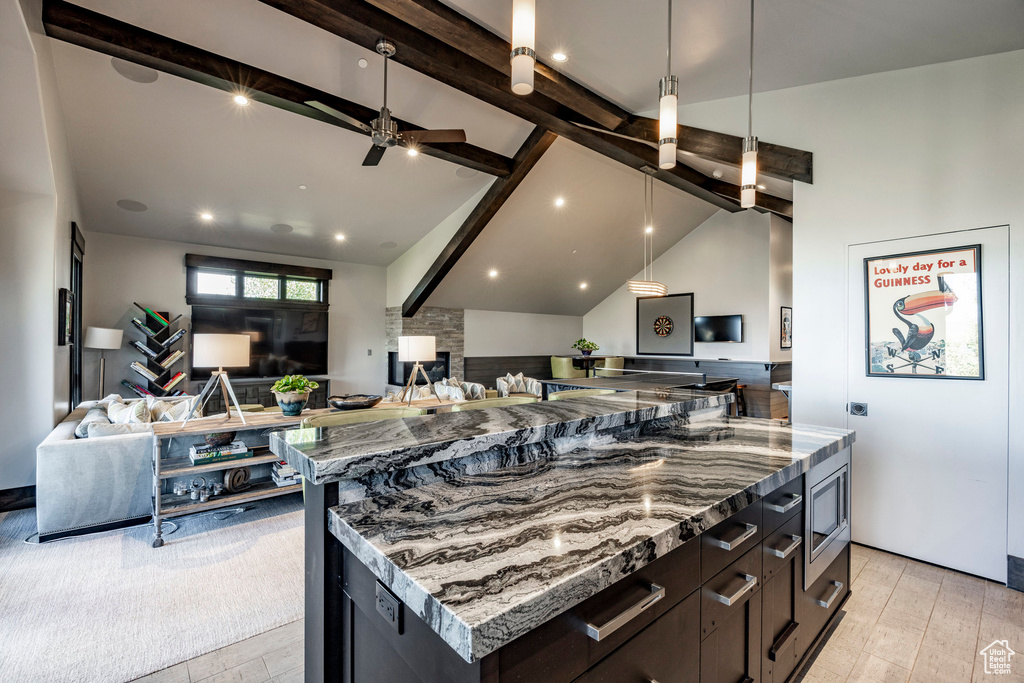 Kitchen with open floor plan, ceiling fan, stainless steel microwave, a fireplace, and pendant lighting