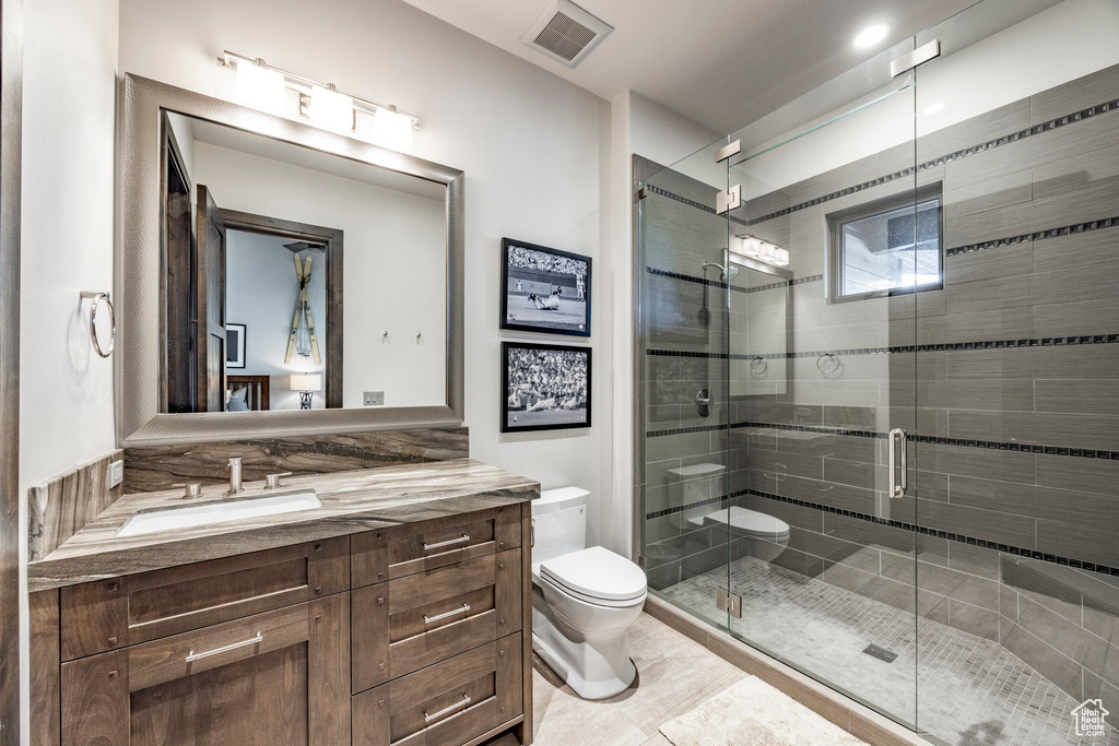 Bathroom featuring toilet, vanity, and a shower stall