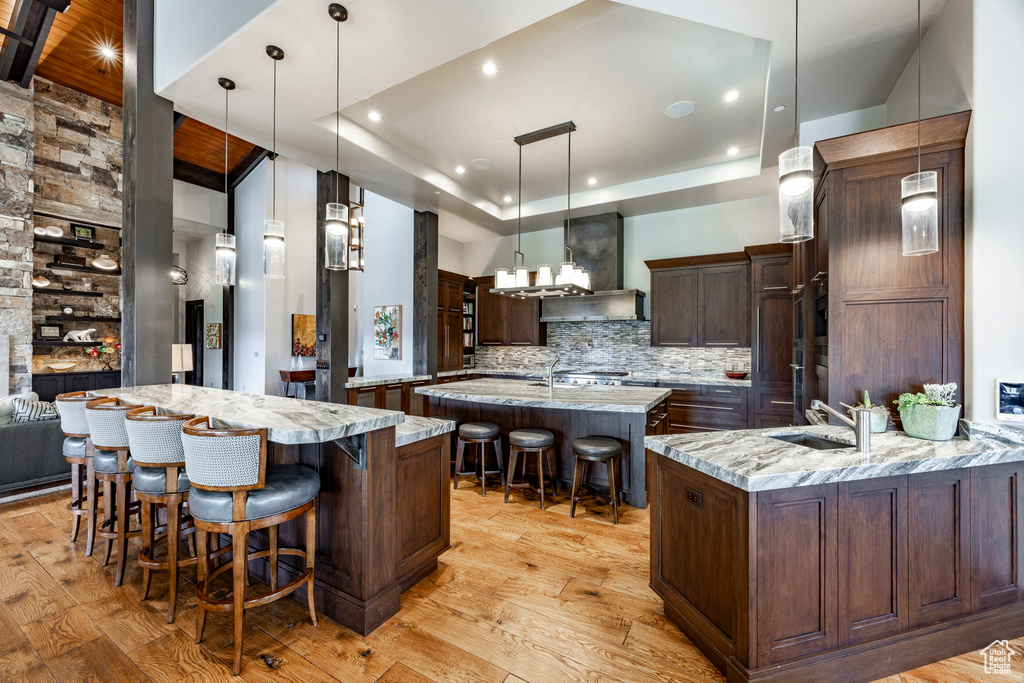 Kitchen featuring a large island with sink, a sink, a kitchen bar, tasteful backsplash, and light wood-style flooring